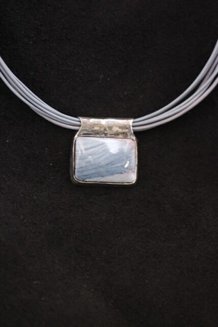12. One a kind sterling silver backed rectangular cabochon of blue slag on multi small leather choker. 2022   1” h  x  1” w --    $2,500